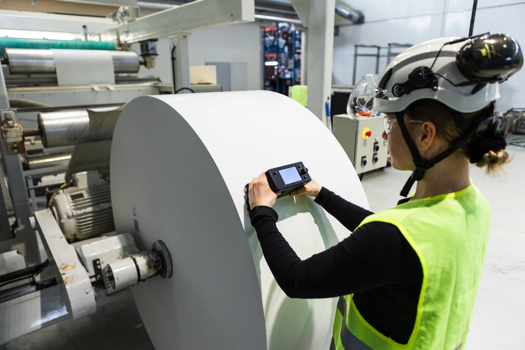Operator measuring a paper roll at the rewinder with RQP Live, the hardness profile on its display.