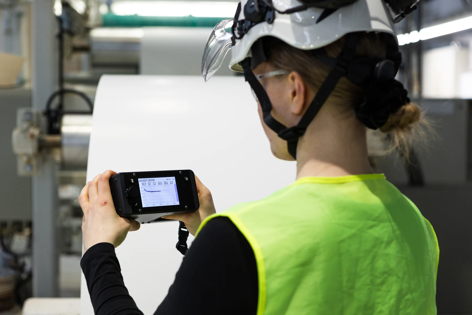 Operator reading a roll hardness profile and its statistics on the Tapio RQP Live display beside the roll.