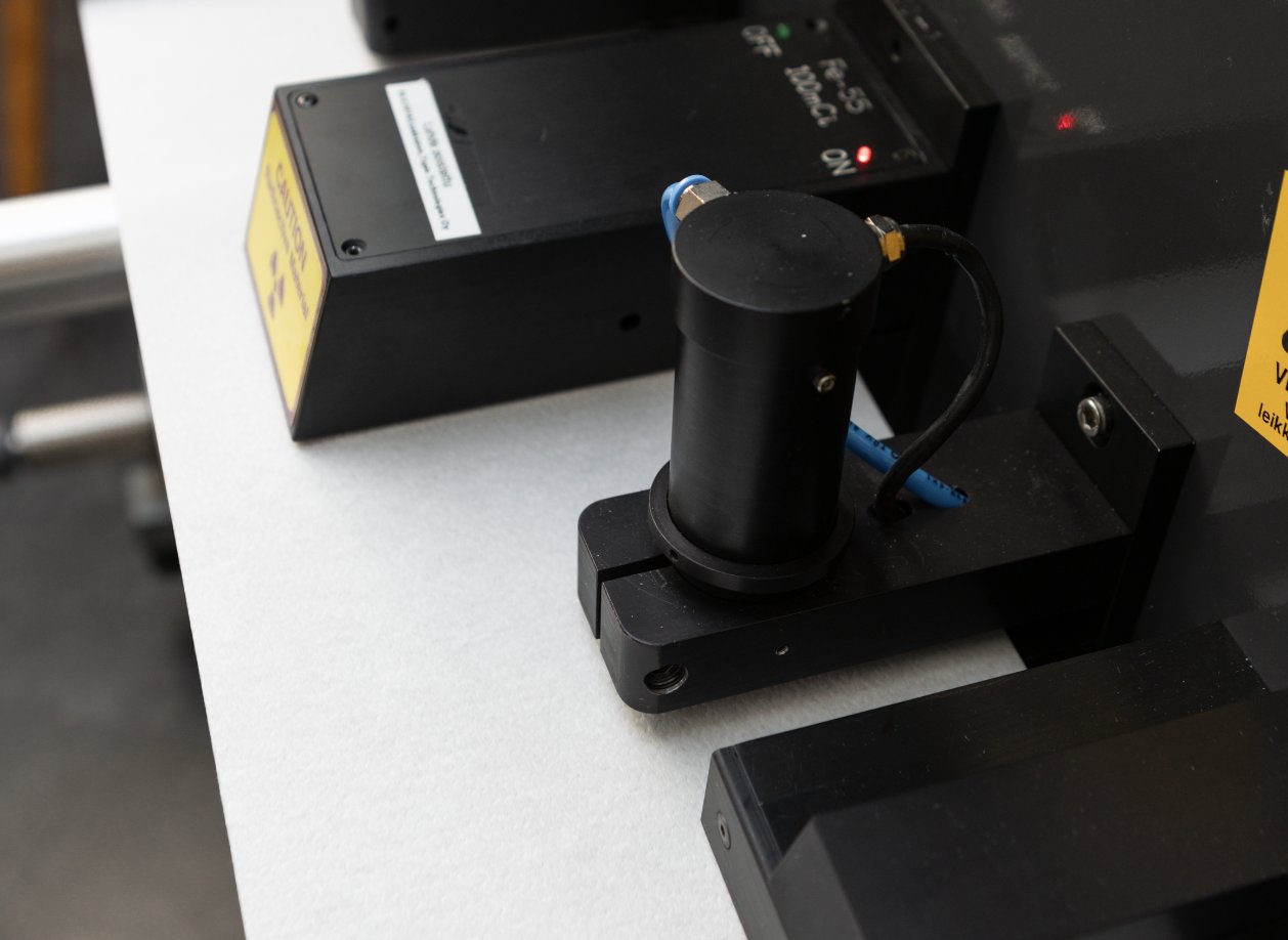 Close-up of the Tapio transmission sensor over the paper strip; its light transmission signal, with caliper, is the input of the basis weight model.
