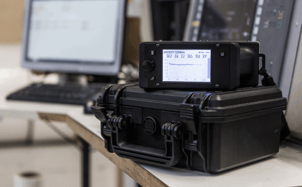 Tapio RQP Live device with a graphical display showing a roll hardness profile, placed on a black protective case in an industrial environment.