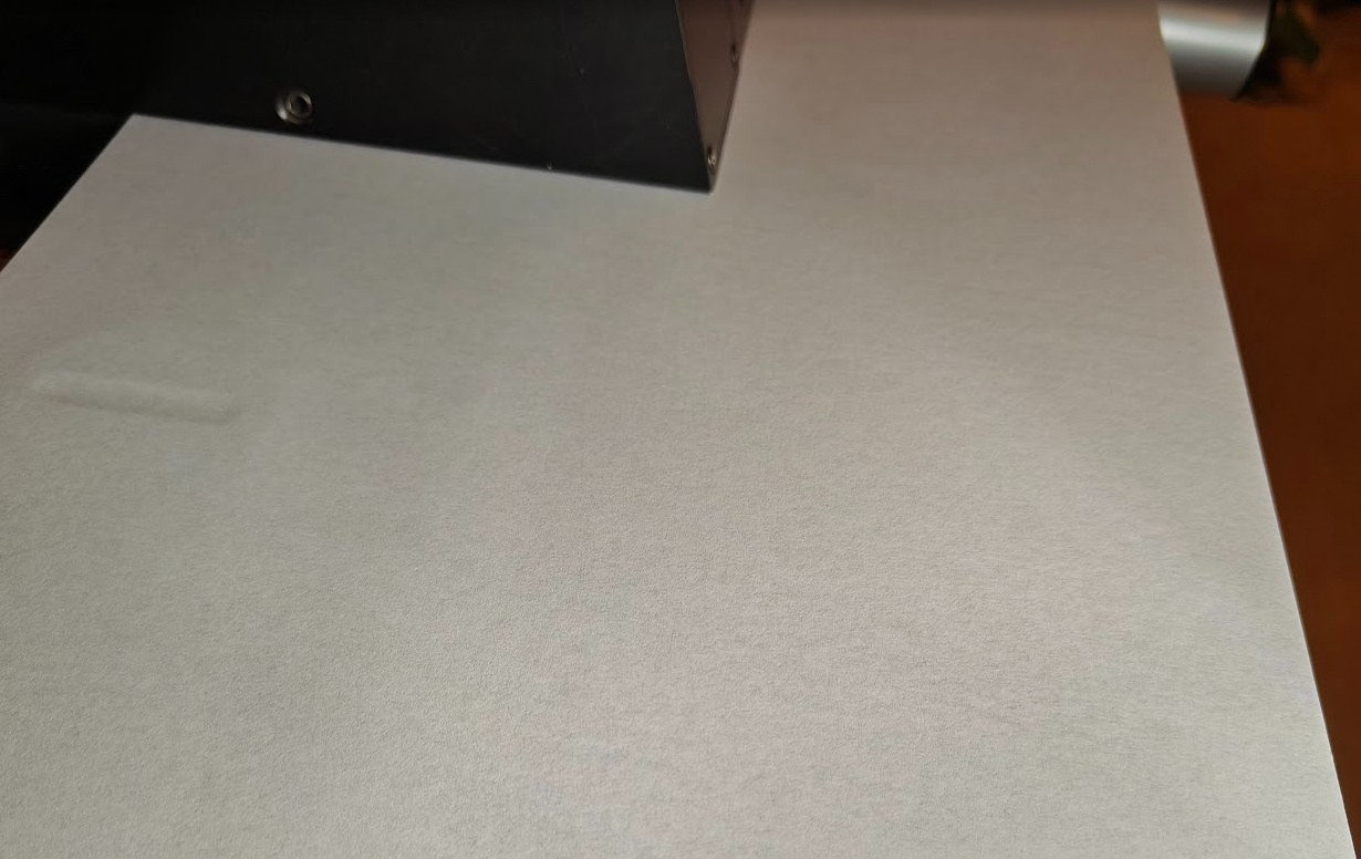 Close-up of a paper sheet surface under a measurement device, illustrating porosity analysis in paper materials.