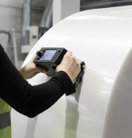 Technician using a handheld measurement device on a large plastic roll surface in an industrial environment